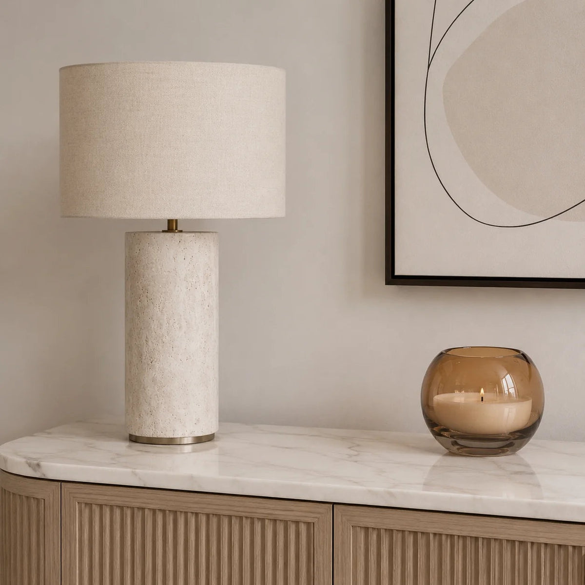 Cortona Travertine Table Lamp — cylinder style on a marble sideboard in daylight