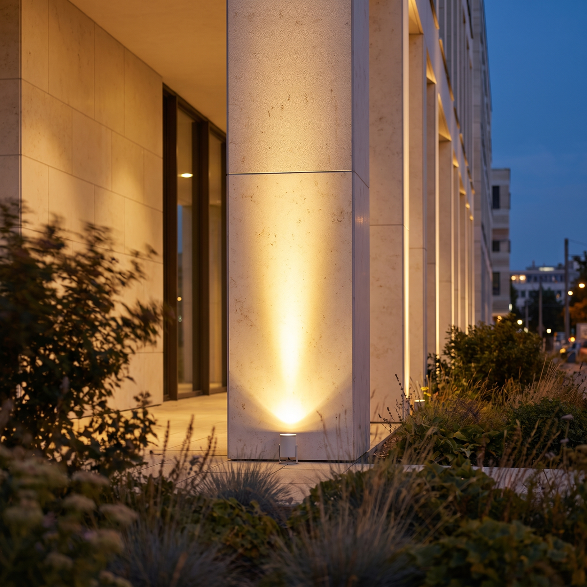 Aperture Beam Spotlight — modern building at dusk with a warm uplight washing a stone pillar