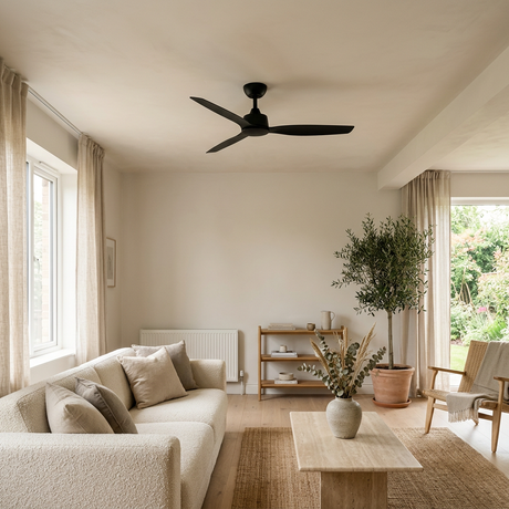 Slim matte-black ceiling fan on a warm off-white plaster ceiling above a boucle sofa and travertine coffee table