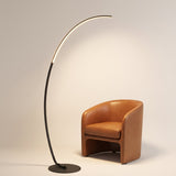Crescent Arc Floor Lamp — Black, arching over a leather studio chair