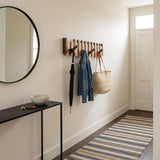 Orlo Piano Key Coat Rack — in a narrow hallway with an umbrella, denim jacket and straw bag