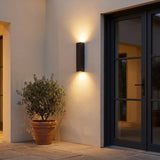 Slab Outdoor Wall Light lit at dusk beside a front entrance