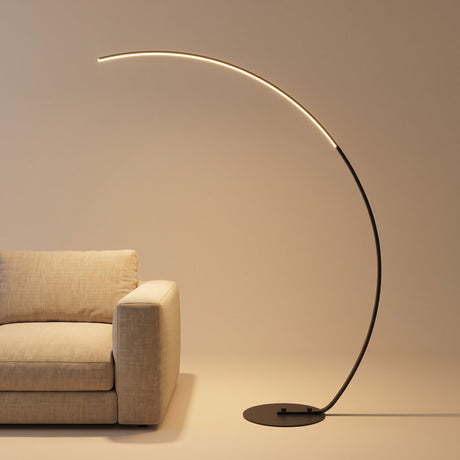 Crescent Arc Floor Lamp — Black, with warm glow over a studio sofa