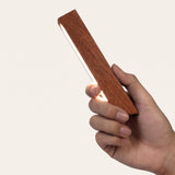 Linea Wood Strip Lamp — Walnut, held in hand for scale
