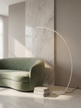 Crescent Arc Floor Lamp — White, in a living room near a marble wall