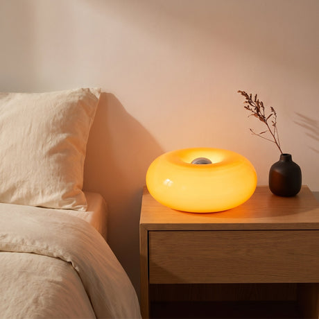 Halo Bauhaus Table Lamp switched on, casting a warm glow on a bedside nightstand