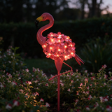 Blossom Flamingo Stake Light - lifestyle image flower bed at dusk