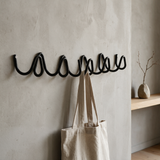 Wave coat rack in a modern entryway with a linen tote and stone vase