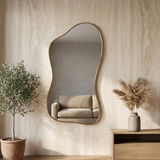 Modern Irregular Floor Mirror, Gold Metal Frame — against a travertine wall