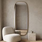Modern Oval Full Length Wall Mirror, Slim Brass Frame — hero with a bouclé chair