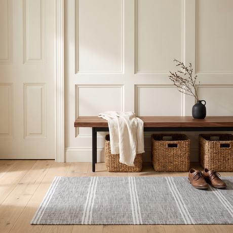 Malta grey striped washable rug in a bright entryway with a walnut bench and seagrass baskets