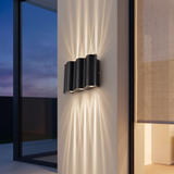 6-light wave wall sconce projecting crossing light beams up and down a limewashed exterior pillar at dusk