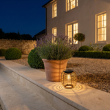 Woven Solar Lantern — Sparse Rattan on a garden step at night
