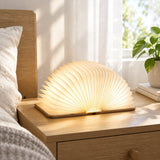 Lumibook Foldable Table Lamp — opened and lit on a nightstand in daylight