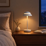 Nomad Cordless Table Lamp — White finish on a bedside table at dusk