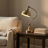 Antique Brass Gooseneck Desk Lamp - lit on a side table in a reading corner